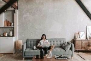 A woman utilizing a laptop in her living room while implementing SEO ranked writing tips.